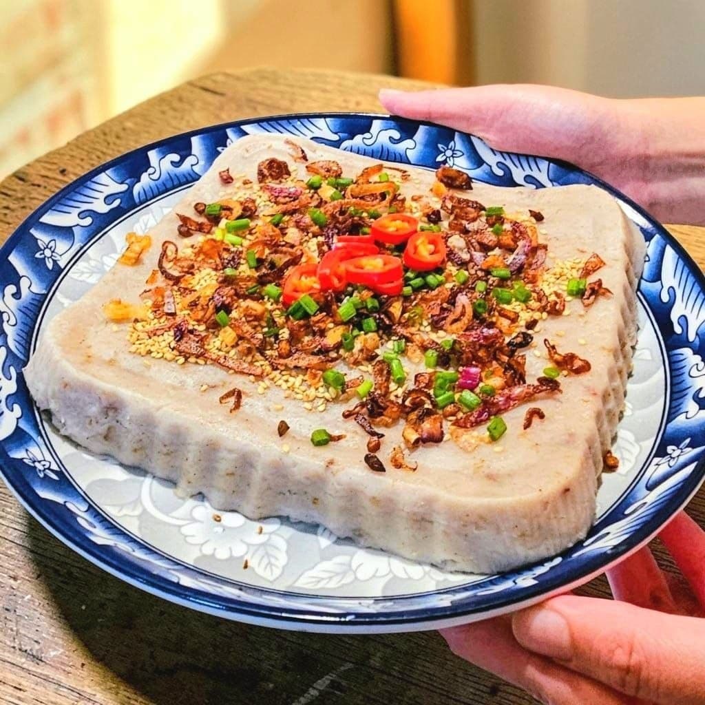 Hands presenting a whole Fatty Yam cake, fresh from the family kitchen
