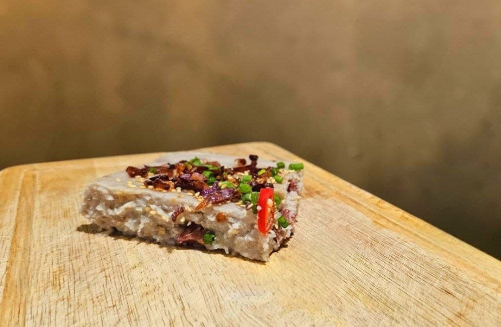 A slice of Fatty Yam's traditional yam cake, topped with fried shallots, spring onion, sesame and red chilli